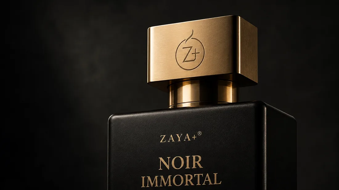 Close detail of the Noir Immortal cap — brushed gold with the engraved ZAYA+ emblem above matte black glass, on a dark background